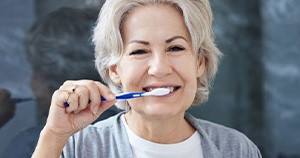 Senior woman brushing her teeth in bathroom