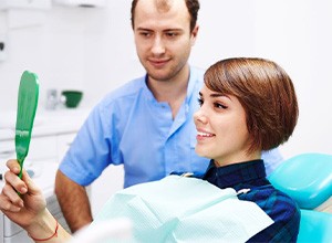 Dental patient holding hand mirror and smiling