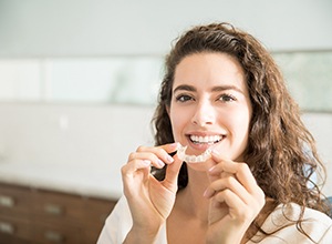 Woman holding Invisalign aligner close to her mouth