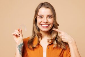 Happy, smiling woman holding Invisalign aligner